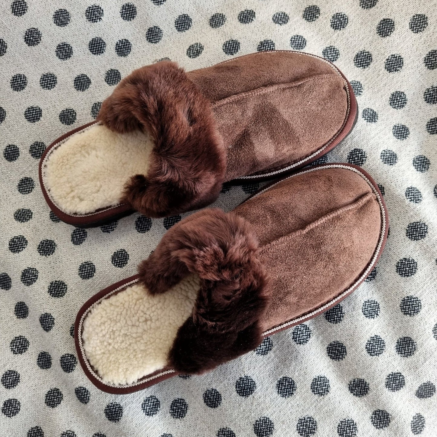 Bruna fårskinnstofflor med mjukt ljust ullfoder och mörkbrun kant, bekväma och varma innetofflor för dam och herr.
