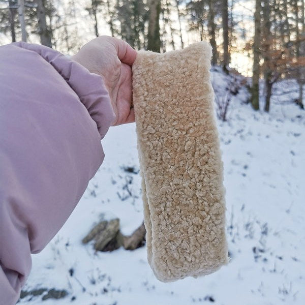 Mjukt och varmt beige teddy pannband för vinterbruk, idealiskt för promenader och friluftsliv i kalla temperaturer.