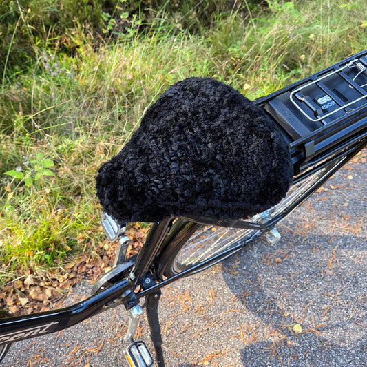 Cykelsadelskydd i svart fårskinn som ger komfort, värme och skydd till cykelsadeln
