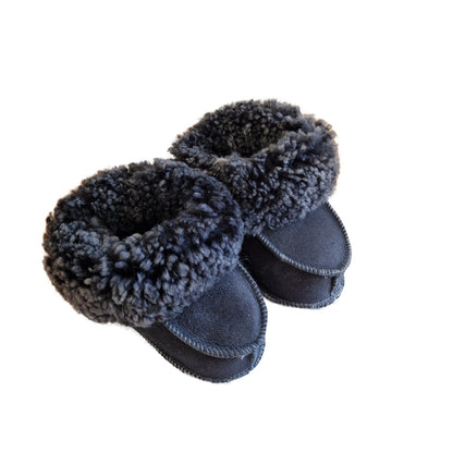 Handgjorda fårskinnstofflor för baby i marinblå färg med mjuk grå ullkant från Jakobs Handmade.