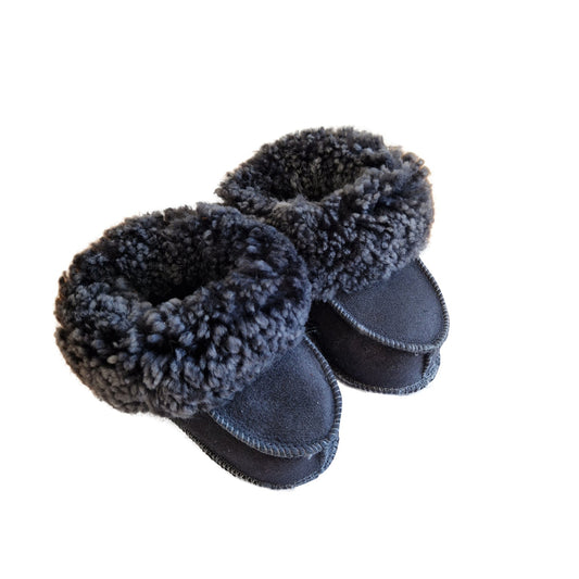 Handgjorda fårskinnstofflor för baby i marinblå färg med mjuk grå ullkant från Jakobs Handmade.