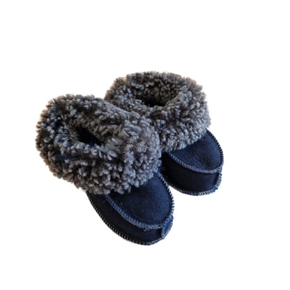 Handgjorda fårskinnstofflor för baby i marinblå färg med mjuk grå ullkant från Jakobs Handmade.