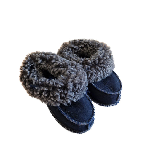 Handgjorda fårskinnstofflor för baby i marinblå färg med mjuk grå ullkant från Jakobs Handmade.