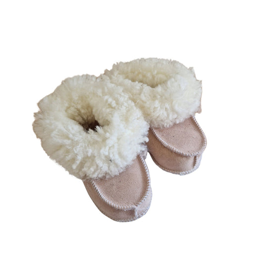 Handgjorda rosa fårskinnstofflor för barn från Jakobs Handmade, sydda i äkta svenskt fårskinn med vit fluffig krage som håller små fötter varma.