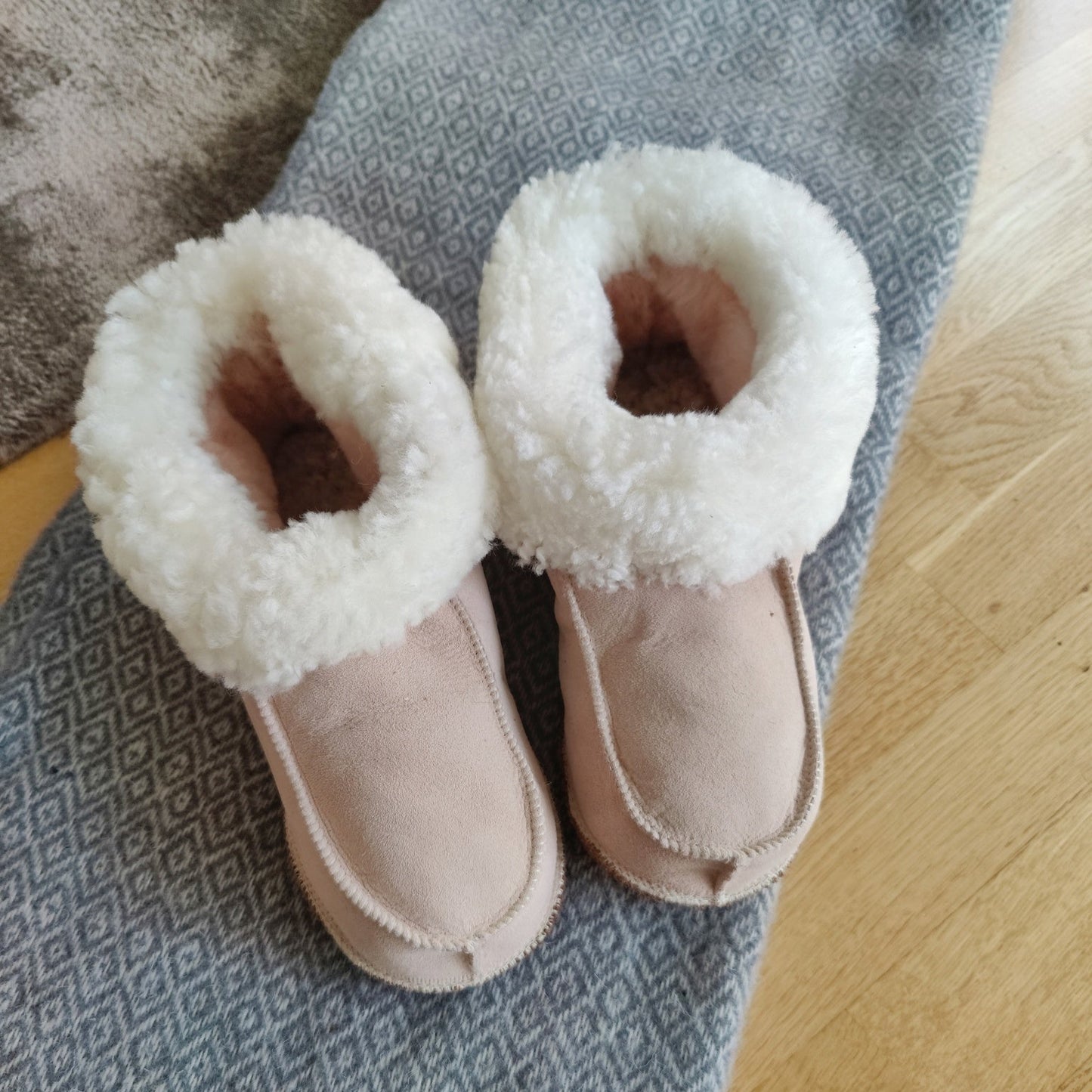 Handgjorda rosa fårskinnstofflor från Jakobs Handmade, tillverkade i äkta svenskt fårskinn med mjuk vit krage för värme och komfort.