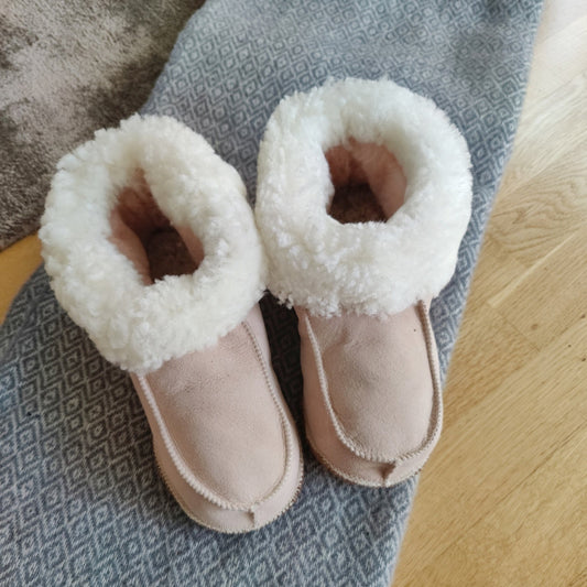 Handgjorda rosa fårskinnstofflor från Jakobs Handmade, tillverkade i äkta svenskt fårskinn med mjuk vit krage för värme och komfort.