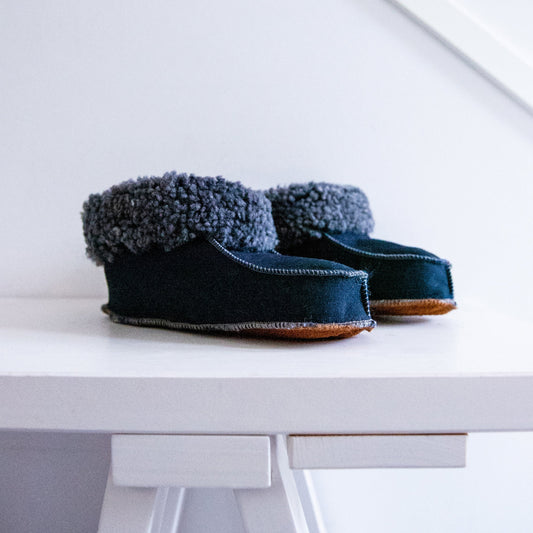 Handgjorda marinblå fårskinnstofflor i äkta svenskt fårskinn från Jakobs Handmade, med tjock mysig krage och slitstark sula.